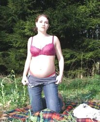 Pregnant dark-haired disrobing in the woods
